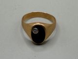an image of a gold ring with a black stone and a diamond