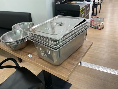 many metal pans on a wooden table in a room