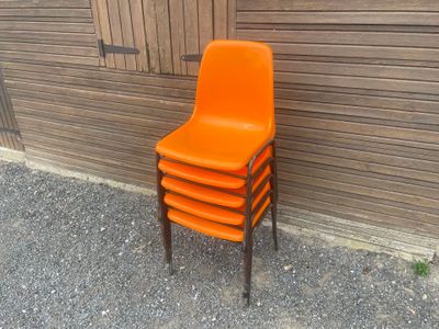a stack of orange chairs sitting next to a wooden wall