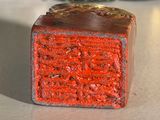 a small red block sitting on a counter next to some jars