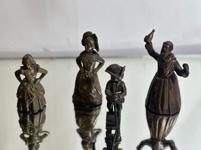 four bronze figurines of people on a glass table