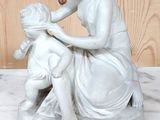 une statue représentant une femme et un enfant assis sur une table