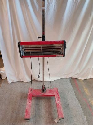 un radiateur rouge posé sur un pied devant un fond blanc