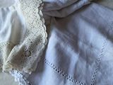 une couverture blanche sur un lit, à côté de deux serviettes blanches