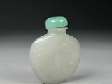 a white glass bottle with a green lid on a white surface