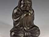 une statue antique en bronze représentant une personne assise en position de méditation