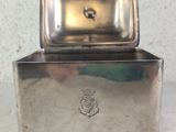 a small metal box with a metal lid on a table