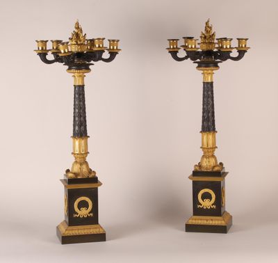 pair of black and gold candelabs with candles on pedestals