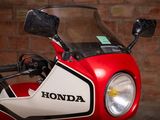 a red and white motorcycle parked in front of a brick wall