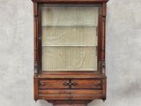 une vieille vitrine en bois avec des étagères en verre, accrochée au mur