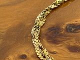 the gold chain is on a wooden table next to a pair of scissors