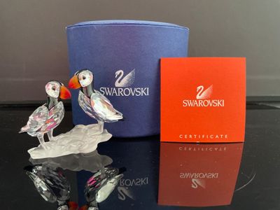 une figurine en verre représentant un oiseau et une boîte posées sur une table
