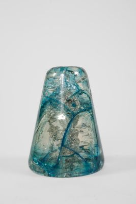 une image représentant un vase en verre bleu posé sur une surface blanche