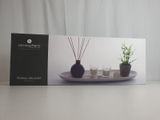La boîte est ouverte sur la table ; elle contient des bougies et une plante.