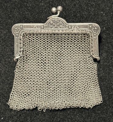 un porte-monnaie argenté entouré d'une chaîne, posé sur une surface noire