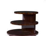 La table à trois niveaux est en bois et possède un piètement circulaire.