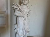 une statue représentant une femme tenant un éventail dans un coin d'une pièce