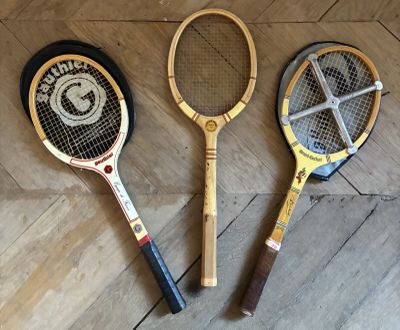 trois raquettes de tennis posées par terre les unes à côté des autres