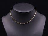 a gold necklace on a mannequin with a black background