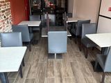 tables and chairs in a restaurant with a brick wall in the background