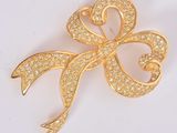 une image représentant une broche en forme de nœud en or sertie de diamants