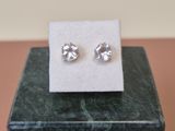 a close up of a pair of earrings sitting on top of a marble block