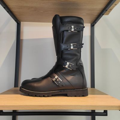une paire de bottes noires posée sur une étagère en bois