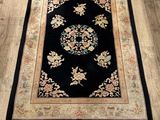 un tapis noir à motifs floraux posé sur un parquet
