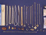 many necklaces and bracelets laid out on a blue surface