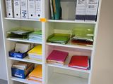 a white bookcase filled with lots of folders and binders