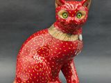 a figurine of a red cat sitting on a black surface