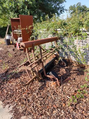 a rusted out machine sitting in the middle of a garden