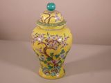 un vase jaune avec un couvercle vert sur lequel est représenté un arbre