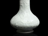 un vase blanc posé sur une surface noire