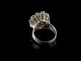 an image of a ring with emerald stones on a black surface