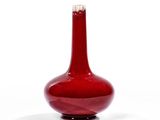 un vase rouge posé sur une surface blanche