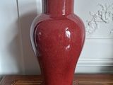 a red vase that is sitting on a wooden table