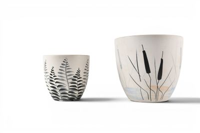 two white cups with black and white designs on them sitting next to each other
