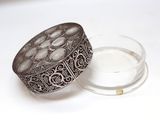a glass container with a silver lid on a white surface