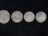 four silver coins are arranged in a row on a black surface