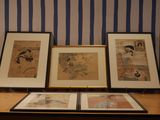 three framed pictures on a table in front of a striped wall