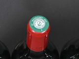 bottles of red wine are lined up in a holder on a table
