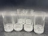six verres à shot alignés sur une table, sur fond noir