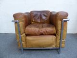 a brown leather chair with a metal frame on the floor