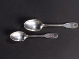 three silver spoons on a black surface with a black background