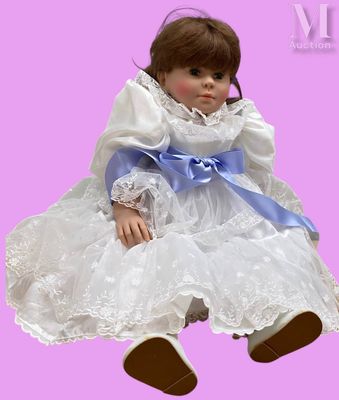 une poupée assise par terre sur un fond rose