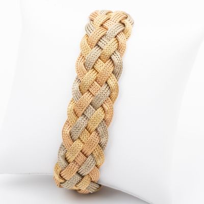 braided bracelet with gold and silver beads on a white pillow