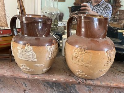deux vases marron posés sur une table, avec un homme à l'arrière-plan
