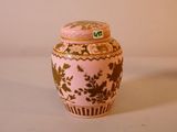 un vase rose et doré posé sur une surface blanche