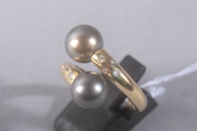 une paire de bagues en perles et diamants posées sur un socle noir